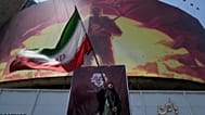 A woman waves an Iranian flag next to a billboard in downtown Tehran, 1 August, 2026