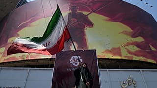 A woman waves an Iranian flag next to a billboard in downtown Tehran, 1 August, 2026