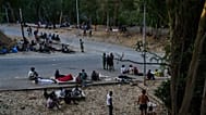 Unos migrantes que cruzaron a España desde Marruecos permanecen sentados frente al centro de acogida temporal de inmigrantes (CETI) en el enclave español de Ceuta