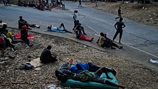 Los migrantes que cruzaron a España desde Marruecos se sientan frente al centro de estancia temporal de inmigrantes (CETI) en el enclave español de Ceuta.