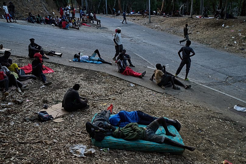 Migrants who crossed into Spain from Morocco sit outside the temporary immigrant centre in the Spanish enclave of Ceuta, 2 August, 2026
