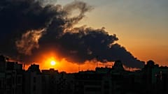 صورة تعبيرية- تغرب الشمس خلف عمود من الدخان يتصاعد جراء ضربة عسكرية أمريكية-إسرائيلية في طهران