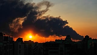 صورة تعبيرية- تغرب الشمس خلف عمود من الدخان يتصاعد جراء ضربة عسكرية أمريكية-إسرائيلية في طهران