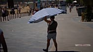Un hombre sostiene un paraguas mientras camina cerca de una playa de Barcelona, España, el miércoles 27 de mayo de 2026.