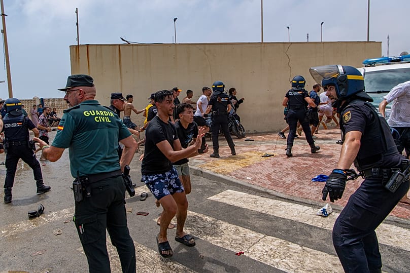 Agentes de la Policía española intervienen mientras unos migrantes cruzan desde Marruecos hacia el enclave español de Ceuta, el jueves 30 de julio de 2026. 