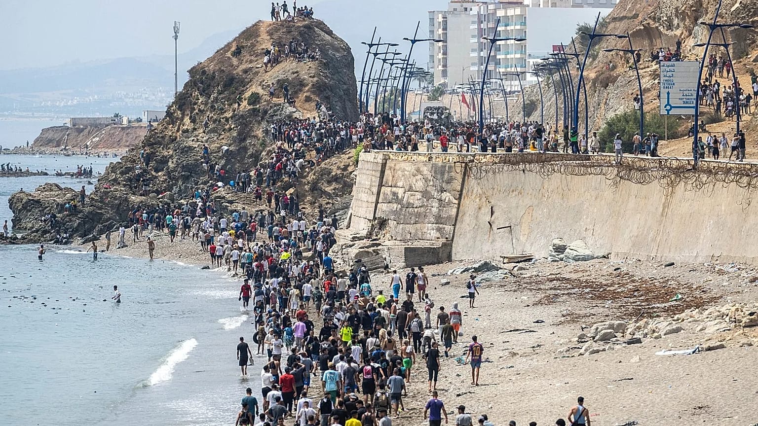 أشخاص يسيرون على الشاطئ بعد محاولة العبور من مدينة الفنيدق المغربية الشمالية إلى جيب سبتة الإسباني