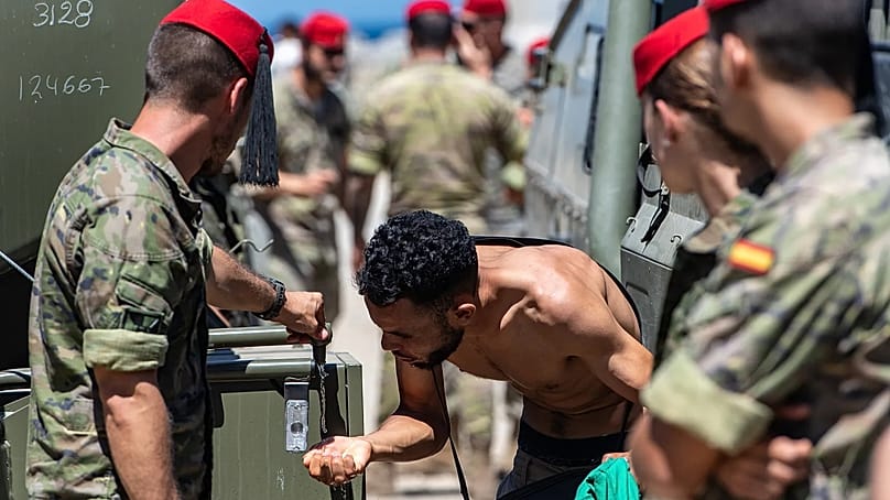 Ein Migrant, der von Marokko nach Spanien gelangt ist, trinkt Wasser, das spanische Soldaten im spanischen Enklave Ceuta am Sonntag, dem zweiten August 2026, verteilen.