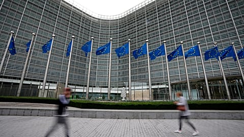 FILE - European Union flags flap in the wind as pedestrians walk by EU headquarters in Brussels. Sept. 20, 2023. 