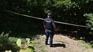Un poliziotto del Kosovo sorveglia il sito dove le squadre forensi hanno iniziato gli scavi di una fossa comune vicino al villaggio di Kalluder, mercoledì 29 luglio 2026