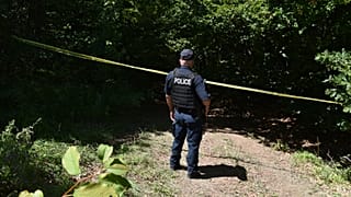 Un poliziotto del Kosovo sorveglia il sito dove le squadre forensi hanno iniziato gli scavi di una fossa comune vicino al villaggio di Kalluder, mercoledì 29 luglio 2026