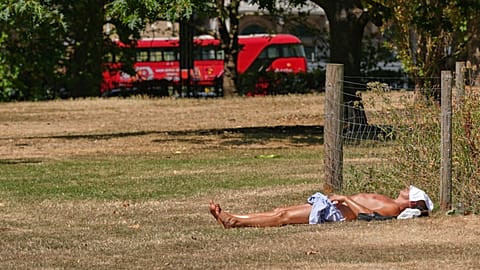 A man sunbathes on dried grass in Green Park in London, as much of the UK is suffering from drought conditions, Monday, Aug. 3, 2026.