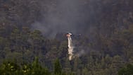 Un hélicoptère bombardier d'eau largue de l'eau au-dessus d’un incendie de forêt près de Correns, dans le sud-est de la France, samedi 1er août 2026.