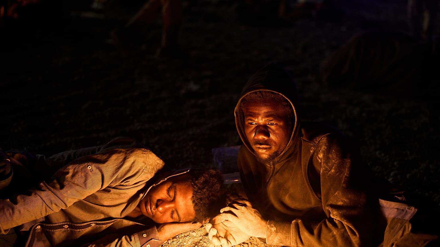 Migrantes que cruzaron a España desde Marruecos se reúnen alrededor de una hoguera en una playa del enclave español de Ceuta, el lunes 3 de agosto de 2026