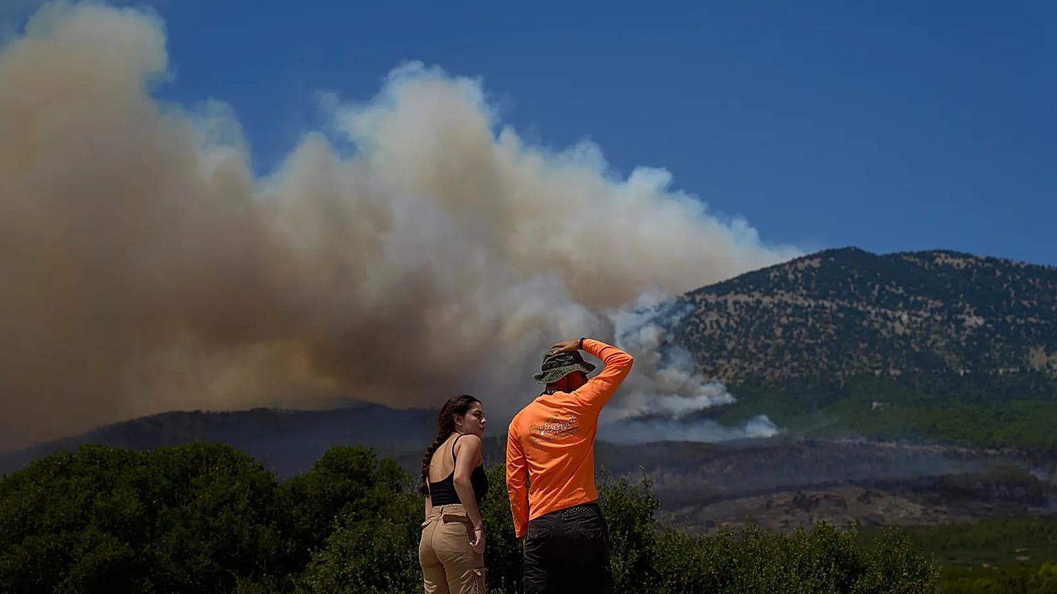 People watch the smoke from a wildfire on Mount Kithairon near Porto Germeno, northwest of Athens, Greece, Monday, Aug. 3, 2026. 