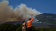 People watch the smoke from a wildfire on Mount Kithairon near Porto Germeno, northwest of Athens, Greece, Monday, Aug. 3, 2026. 