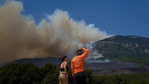 People watch the smoke from a wildfire on Mount Kithairon near Porto Germeno, northwest of Athens, Greece, Monday, Aug. 3, 2026. 