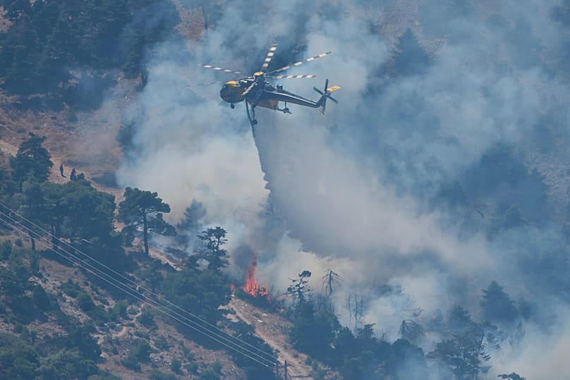 A firefighting helicopter drops water over a wildfire on Mount Kithairon near Porto Germeno, 3 August, 2026