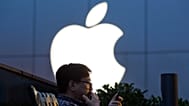 FILE - In this Friday, May 13, 2016, file photo, a man uses his mobile phone near an Apple store in Beijing. Apple reports financial results July 26, 2016.