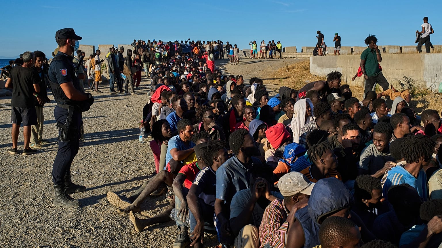 Migrants who crossed from Morocco into Spain line up for food distribution on a beach in the Spanish enclave of Ceuta, 3 August, 2026