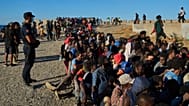 Migrants who crossed from Morocco into Spain line up for food distribution on a beach in the Spanish enclave of Ceuta, 3 August, 2026