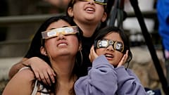 Espectadores usam óculos especiais para observar a lua a colocar-se entre o sol e a provocar o eclipse solar anular, ou anel de fogo, sábado, 14 de outubro de 2023