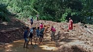 People clean a stretch of a road that covered with mud following heavy rain in Nawalapitiya, 4 August, 2026