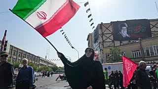 امرأة تلوّح بعلم إيران خلال شعائر الأربعين في طهران، وخلفها لافتة للمرشد الأعلى الراحل علي خامنئي، 4 أغسطس 2026.