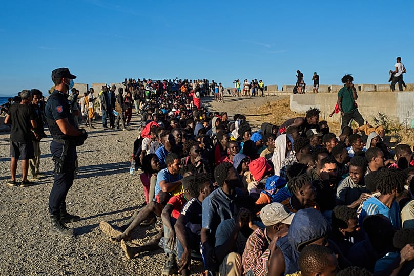 Migrants who crossed from Morocco into Spain line up for food distribution on a beach in the Spanish enclave of Ceuta, 3 August, 2026