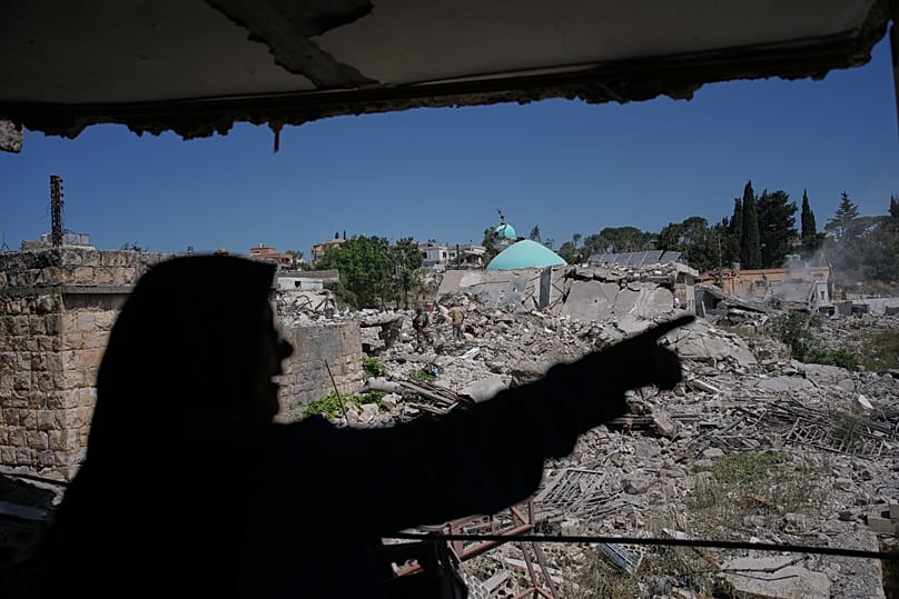 A woman gestures toward the rubble of her neighbourhood from inside her destroyed home in Zawtar al-Gharbieh, 28 July, 2026