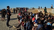 Migrants who crossed from Morocco into Spain line up for food distribution on a beach in the Spanish enclave of Ceuta, 3 August 2026