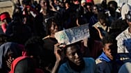 Un migrante sostiene un cartel que pone "asilo"