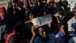 Un migrante sostiene un cartel que pone "asilo"