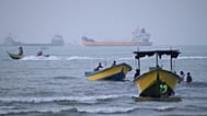 Small boats line the shore as cargo ships and other commercial vessels appear anchored in the Strait of Hormuz off Bandar Abbas, Iran, Monday, July 27, 2026.