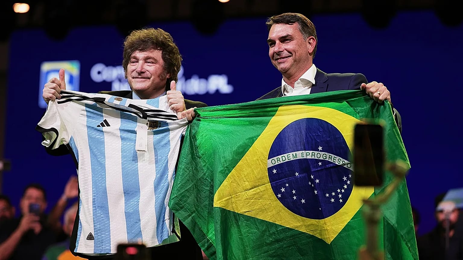 Brazilian Sen. Flavio Bolsonaro holds a Brazil national flag as Argentina's President Javier Milei holds an Argentina local selection jersey