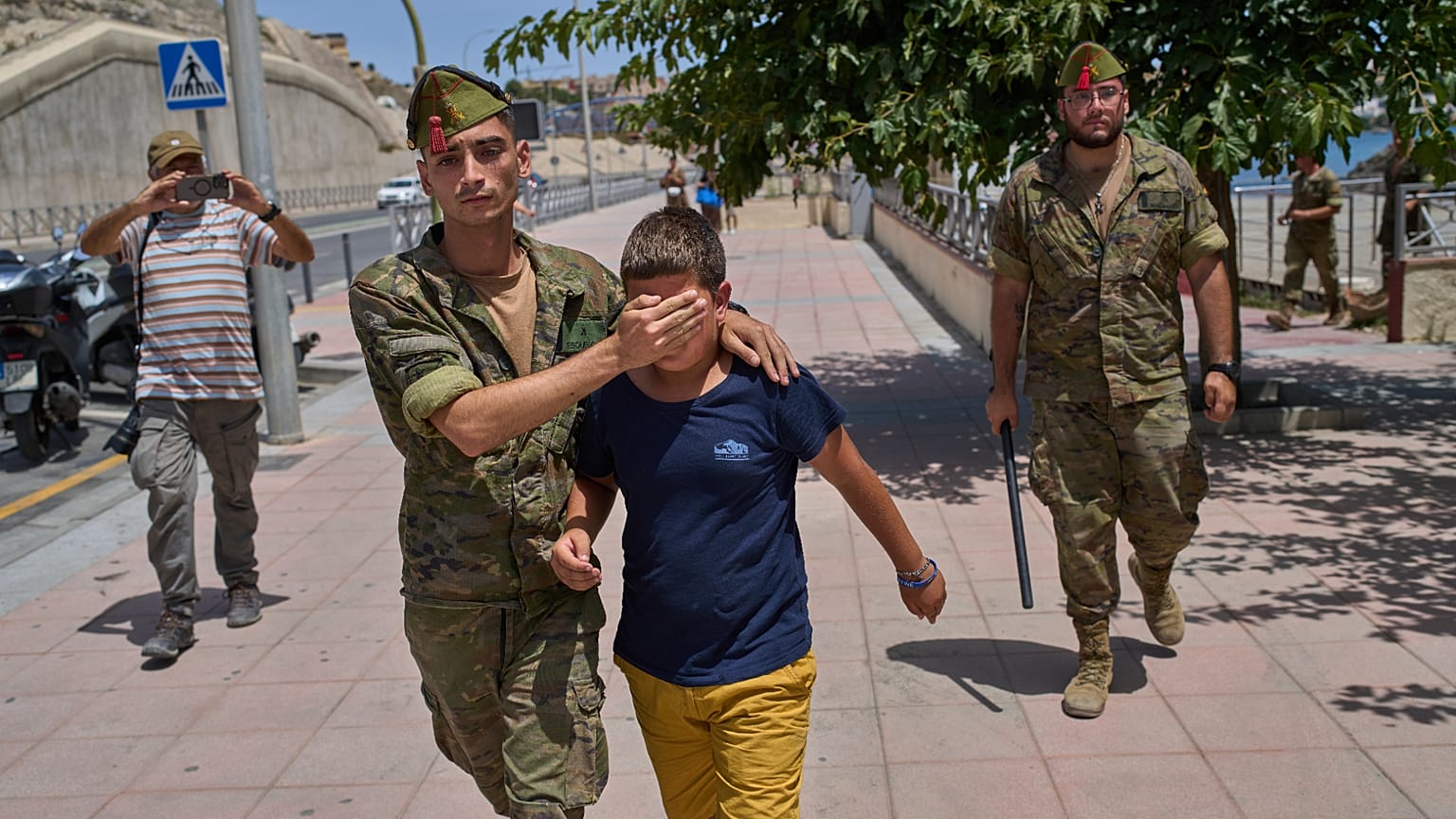 Un menor no acompañado de 12 años que había cruzado a España es escoltado por un soldado español hasta la frontera entre España y Marruecos desde el enclave español de Ceuta, 