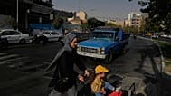 امرأة تعبر الشارع مع فتاة في وسط مدينة طهران، إيران، الأربعاء 22 يوليو 2026. (AP Photo/فاهد سليمي)