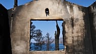 The sea is visible through the remains of a house destroyed by a wildfire in Porto Germeno, 4 August, 2026