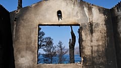 The sea is visible through the remains of a house destroyed by a wildfire in Porto Germeno, 4 August, 2026