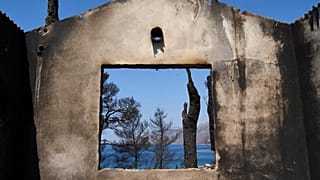 The sea is visible through the remains of a house destroyed by a wildfire in Porto Germeno, 4 August, 2026