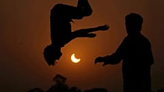 Dos jóvenes saltan en un trampolín en las afueras de Lahore, Pakistán, en un eclipse parcial del 25 de octubre de 2022