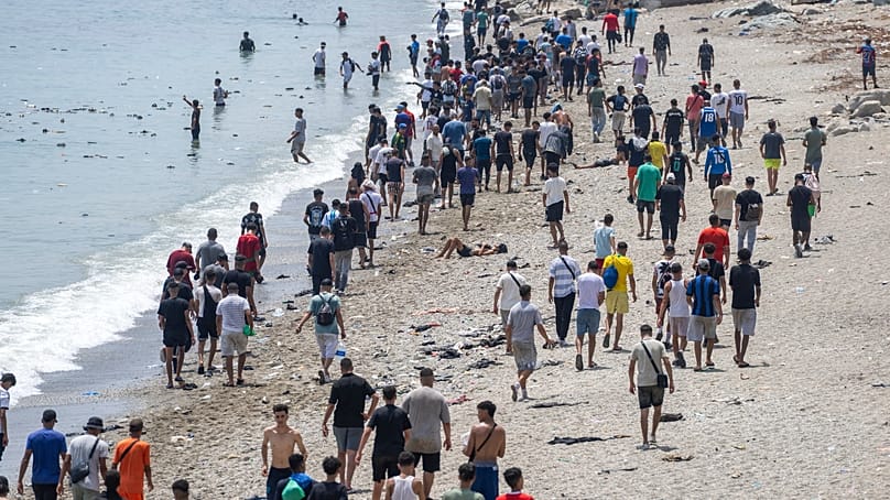 People walk on a beach after attempting to cross from the Moroccan northern town of Fnideq to the Spanish enclave of Ceuta, 31 July, 2026. 