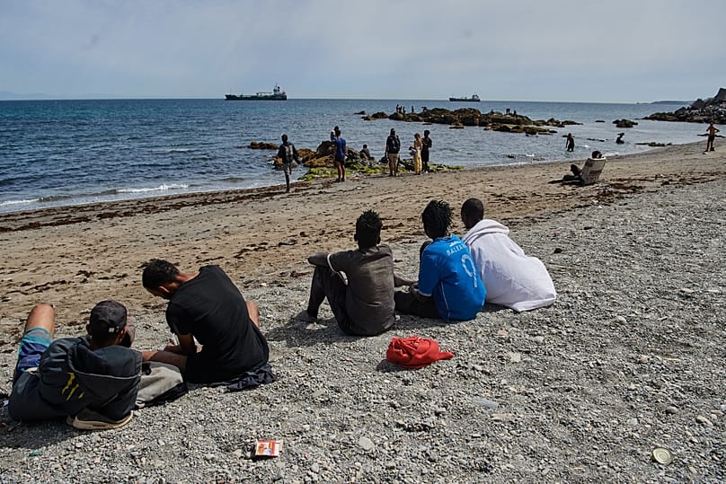 Des migrants qui ont traversé la frontière entre le Maroc et l'Espagne se rassemblent sur une plage de l'enclave espagnole de Ceuta, ce lundi 3 août 2026.