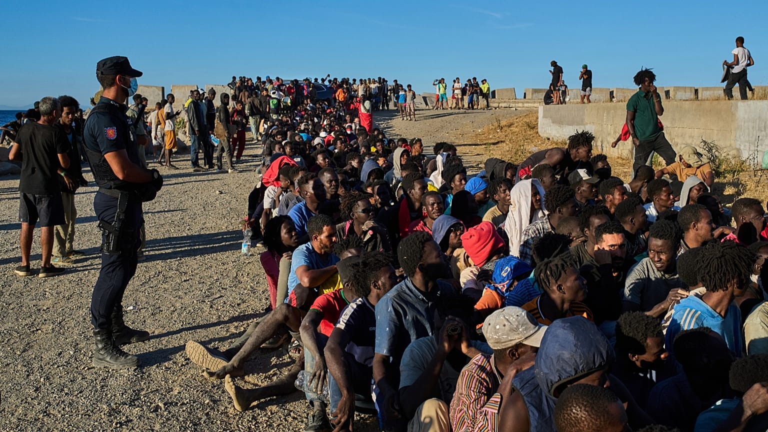 Migrants who crossed from Morocco into Spain line up for food distribution on a beach in the Spanish enclave of Ceuta, 3 August, 2026