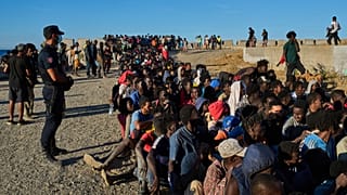 Migrants who crossed from Morocco into Spain line up for food distribution on a beach in the Spanish enclave of Ceuta, 3 August, 2026