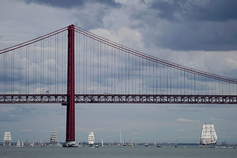 Le navire-école Sagres, à droite, mène un défilé de grands voiliers sur le Tage, avec le pont du 25 Avril en arrière-plan, à Lisbonne, le 3 septembre 2023