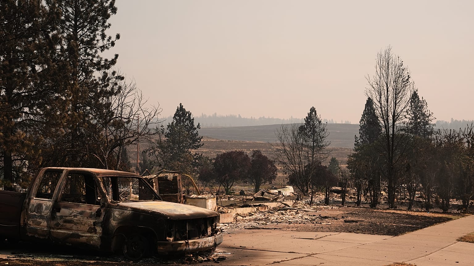 Burned truck stands near homes destroyed by wildfire in north Spokane, Wash., Tuesday, Aug. 4, 2026.