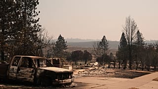 Burned truck stands near homes destroyed by wildfire in north Spokane, Wash., Tuesday, Aug. 4, 2026.