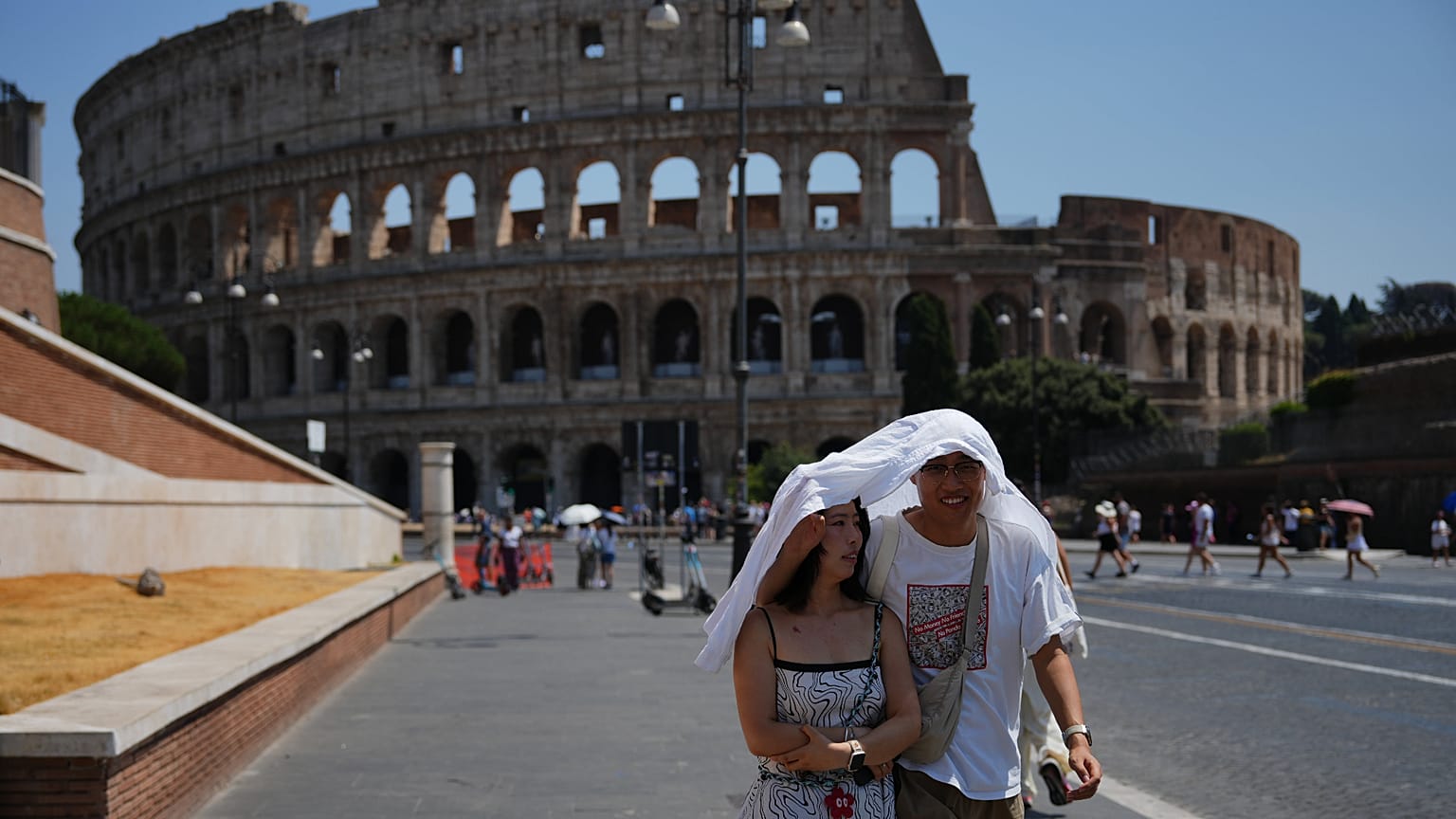 ARCHIVIO - Turisti cercano riparo mentre camminano davanti all'antico Colosseo di Roma, 1 agosto 2026.