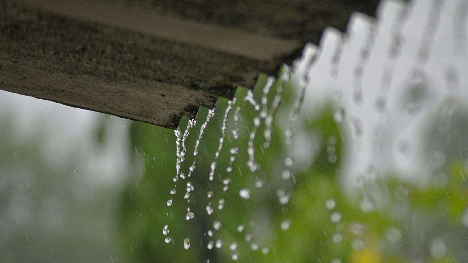 Plano detalle del agua de lluvia cayendo desde un tejado.