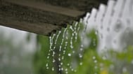 Plano detalle del agua de lluvia cayendo desde un tejado.